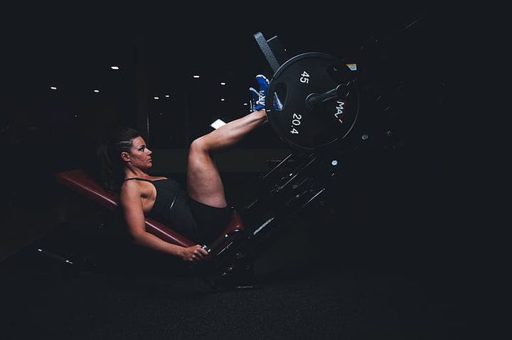 A person training on a leg press in a dimly lit gym